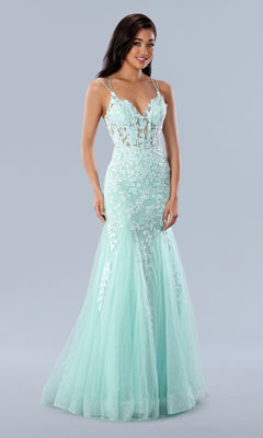 A woman stands against a grey background wearing the Long Prom Dress 24229 by Stella Couture—a light blue, fitted mermaid gown with lace embroidery, a sheer bodice, and thin straps.