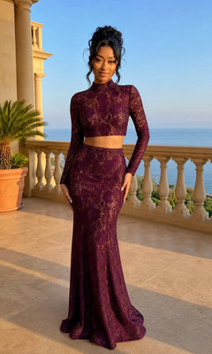 A woman in a long-sleeved, garnet Lace Two-Piece Long Prom Dress stands on a terrace with a stone balustrade, the sea and sky stretching out behind her.