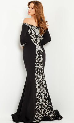 A woman models the Jovani Long Black and White Formal Dress 24328, featuring an off-the-shoulder design with silver embroidery down the back, standing against a plain white background.