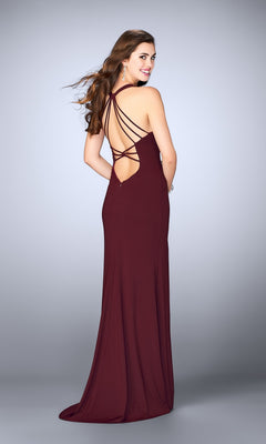 Woman wearing the La Femme Dress 24355 in burgundy, featuring a strappy open back, stands and looks over her shoulder against a plain background.