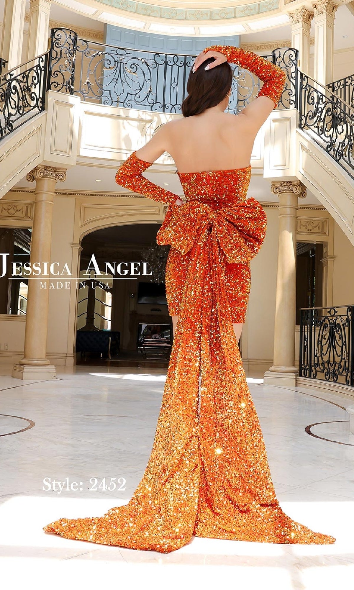 A woman wears the Gloved Short Sequin Hoco Dress: Jessica Angel 2452—an orange strapless mini dress with a large bow and long train—in an elegant room with columns and a balcony. Text reads 