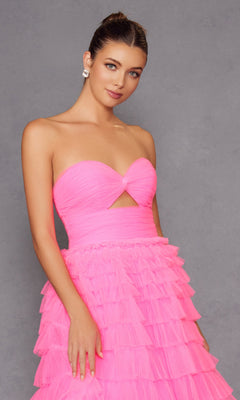 A woman stands against a plain gray background wearing the Long Prom Dress JT2456H by Juliet, a strapless bright pink ball gown featuring ruffle tulle and a cutout detail at the bodice.