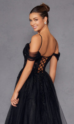 Woman wearing the Sheer-Waist Long Prom Ball Gown (Juliet JT2466A), featuring a black off-the-shoulder design and lace-up back, poses turned slightly to the side and smiles against a plain gray backdrop.