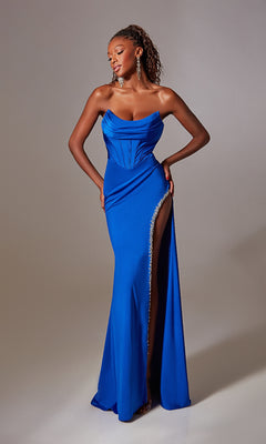 A woman poses gracefully against a plain backdrop in the Aerie Couture 249, a strapless royal blue long prom dress featuring a corset-style waist and rhinestone-trimmed side slit.