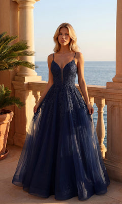 A woman in a navy Glitter Tulle A-Line Prom Dress (PromGirl 250032) stands on a stone balcony overlooking the sea at sunset.