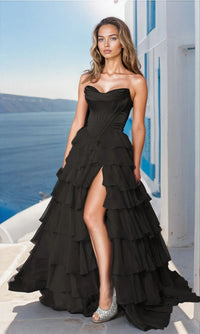 A woman in a black strapless long ruffled prom ball gown with a sweetheart neckline and a side slit.