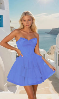 Woman in a short periwinkle dress standing in a picturesque Mediterranean setting with white buildings and blue sky.