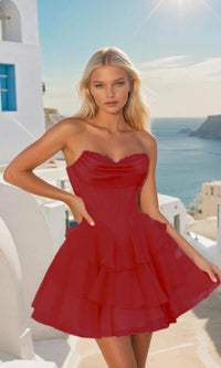 Woman in a short red dress standing in a scenic location with ocean and buildings in the background