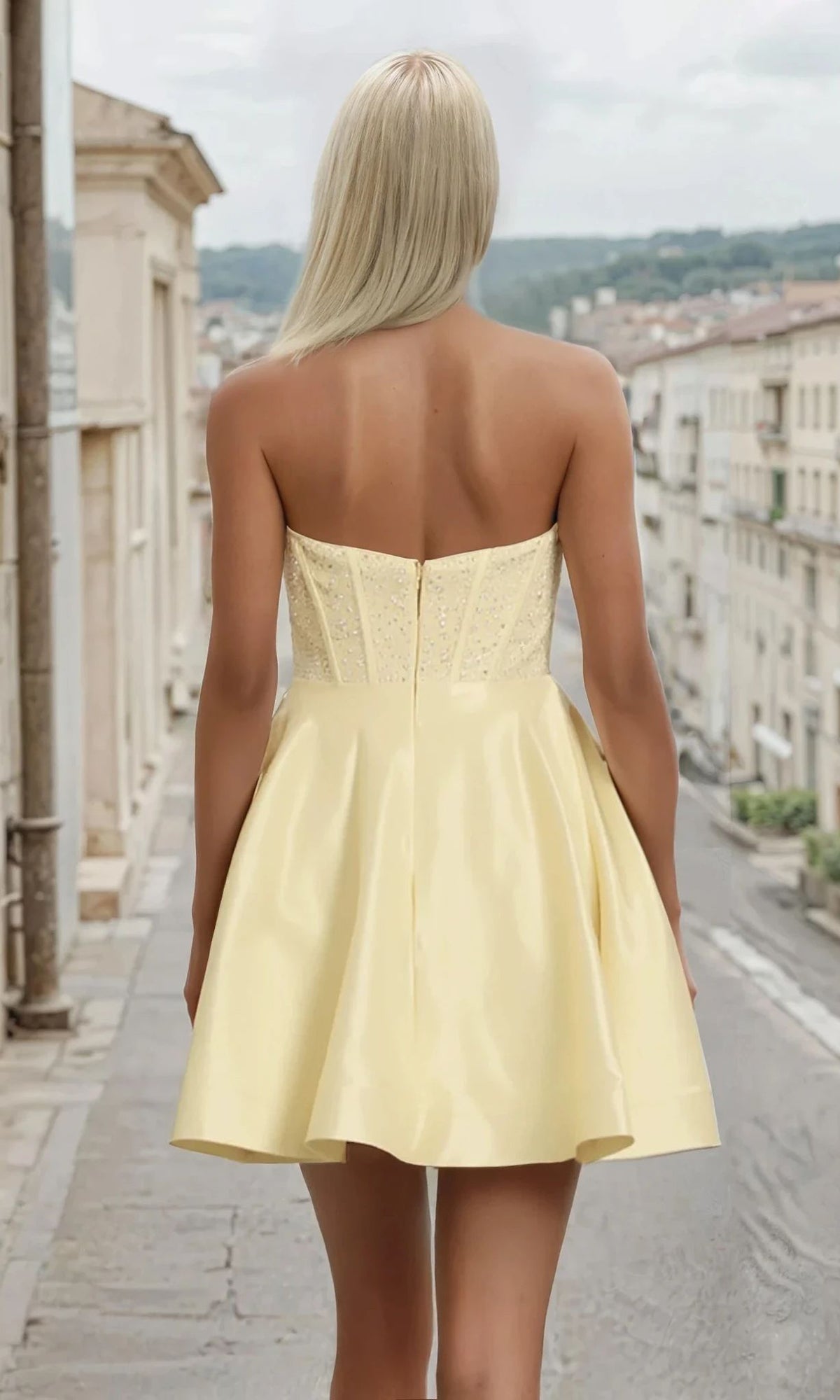 Woman showing the back of a yellow dress, standing on a street.