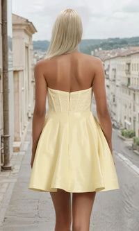 Woman showing the back of a yellow dress, standing on a street.
