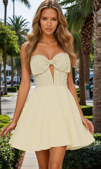 Woman wearing a strapless dress with a bow detail in an outdoor setting.