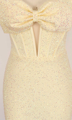 Close-up of the PromGirl Exclusive 250142 homecoming dress, a light yellow strapless design adorned with dazzling rhinestones, featuring a large bow on the bodice, sheer mesh panel, and structured corset-style seams.
