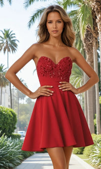 Woman wearing a red strapless dress with floral details in a palm tree-lined street.