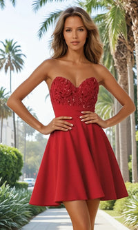 Woman wearing a red strapless dress with floral details in a palm tree-lined street.