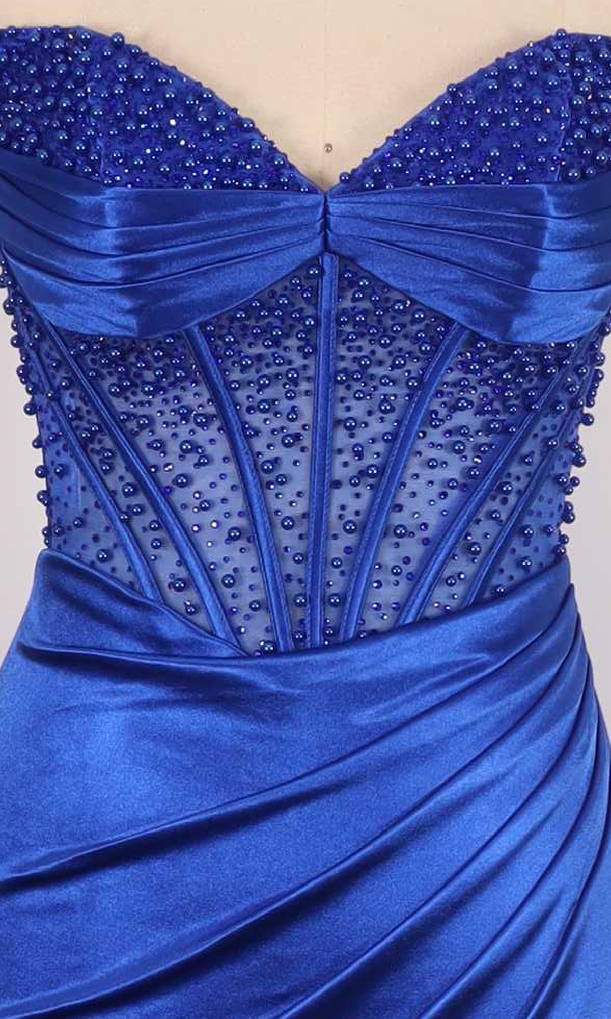 Close-up of a royal blue dress with pearl embellishments on a sheer corset bodice