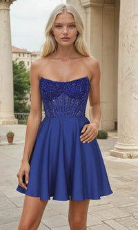 Woman wearing a blue short strapless dress with intricate detailing in an outdoor setting.