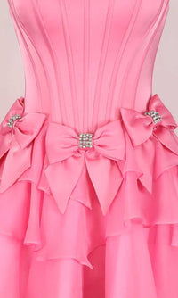 Close-up of a pink dress with embellished bows around the waistline on a light background