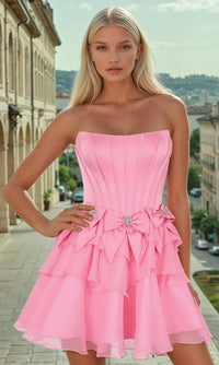 Woman wearing a pink strapless short dress with bows, with an outdoor urban background.