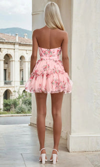 Woman wearing a pink floral dress standing in an outdoor setting with classical architecture.