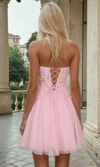 Woman wearing a short pink dress and showing the lace-up back of the dress in an outdoor setting