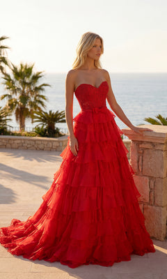 A woman in the Chiffon and Lace Prom Gown: PromGirl Exclusive 250238 stands outdoors on a stone terrace with palm trees and the ocean in the background.