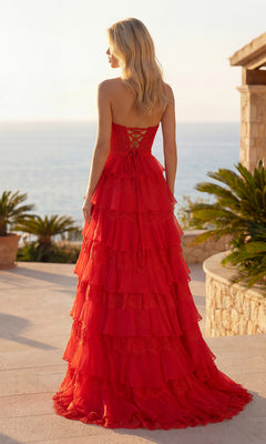 Wearing the Chiffon and Lace Prom Gown: PromGirl Exclusive 250238, a woman stands outdoors in front of the ocean, surrounded by palm plants and elegant stone architecture.