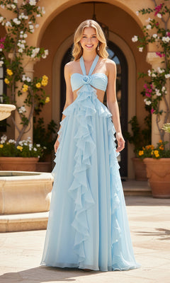 A woman stands outdoors wearing the PromGirl Exclusive 250269 long prom dress in light blue, featuring a halter neckline, open back, floor-length ruffled skirt, and a rosette detail at the chest.