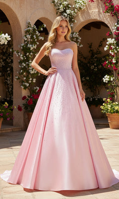 A woman in a pink strapless satin PromGirl Exclusive 250297 prom dress with rhinestone embellishments stands outdoors on a stone patio, surrounded by potted plants and flowering vines.