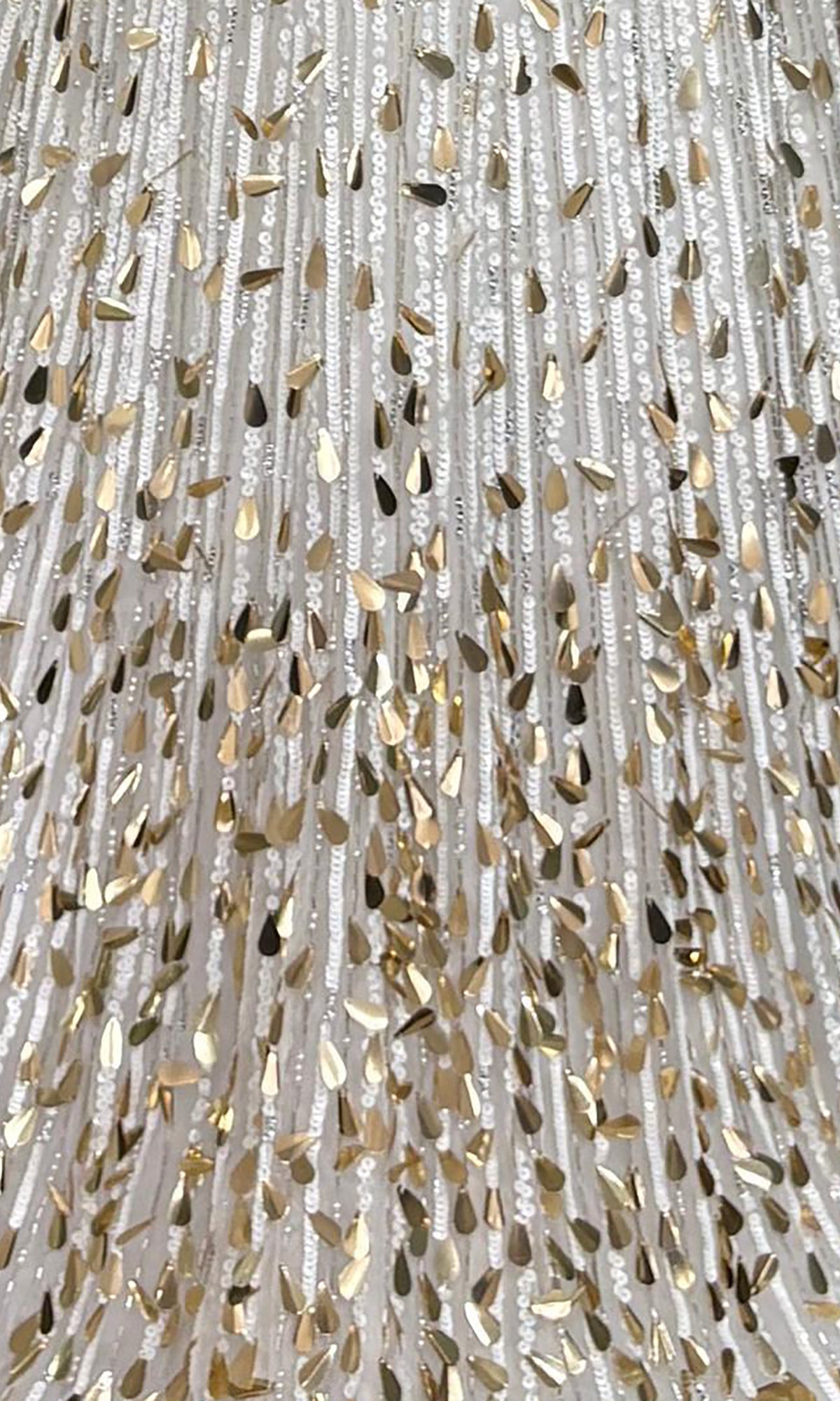 Close-up of the white fabric on the Sparkly Sequin Prom Dress: PromGirl Exclusive 250304, showing vertical sequin rows and metallic gold accents that create a shimmering, textured look.