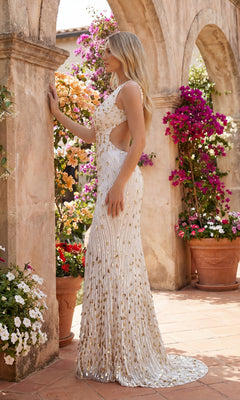 A woman in the Sparkly Sequin Prom Dress: PromGirl Exclusive 250304 stands by a stone archway, surrounded by potted flowers and lush greenery.