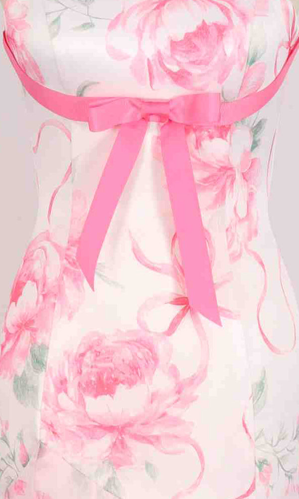 Close-up of the PromGirl Exclusive 250333: a long white prom dress with pink floral prints, featuring a pink ribbon bow at the waist.