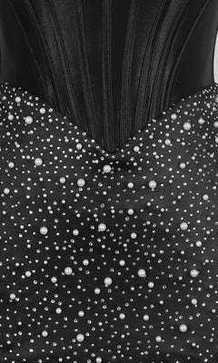 Close-up of the PromGirl Exclusive 250344, a black corset homecoming dress with a structured bodice and an embellished bodycon skirt decorated with white pearls in various sizes.