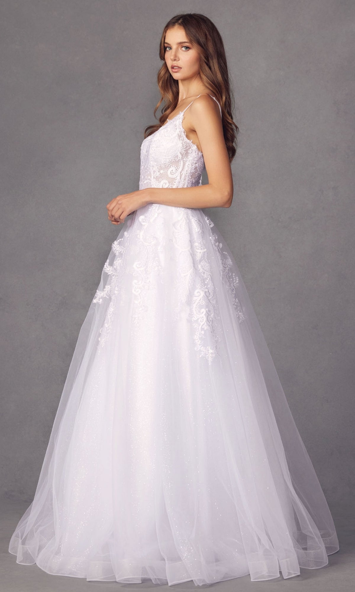 A woman stands in profile wearing the Embroidered Glitter-Tulle Long Prom Ball Gown 251—a sleeveless white dress with lace details and a full tulle skirt—set against a plain gray background.