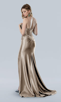 A woman stands facing away, looking over her shoulder in the Stella Coture 25194 Cut-Out Strapless Prom Gown, a metallic gold satin dress, set against a plain light gray background.