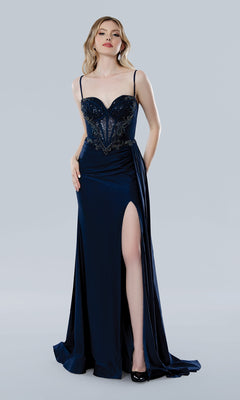 A woman wears the Stella Couture 25224, a navy blue long prom dress featuring an embellished sweetheart bodice, thin straps, and a high thigh slit, standing against a plain light background.