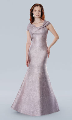 A woman stands against a light gray background wearing the Stella Couture 25329, a long formal dress in rose with a fitted, off-the-shoulder mermaid silhouette and flared hem.