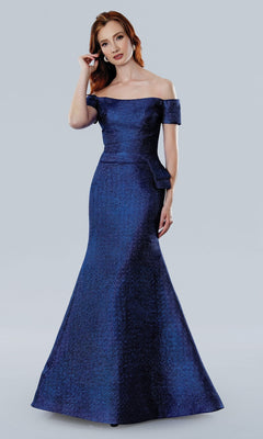 A woman wears the Stella Couture 25331 long formal dress in royal, featuring an off-the-shoulder design and a fitted silhouette that flows to the floor, set against a plain light gray background.