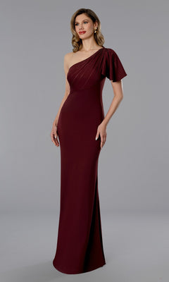 A woman stands against a plain gray background wearing the Stella Couture 25358, a long formal wine-colored dress featuring a floor-length one-shoulder design with draped sleeve and back zipper closure.