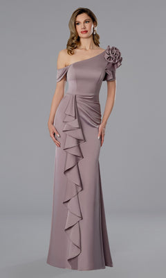 A woman wears the Stella Couture 25360 long formal dress in rose, featuring an asymmetrical neckline, a bold 3D flower on one shoulder, and a cascading front ruffle.