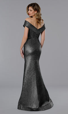 A woman models the Stella Couture 25365 Long Formal Dress with off-the-shoulder, textured metallic fabric, standing against a plain gray background and turning her head to the side.