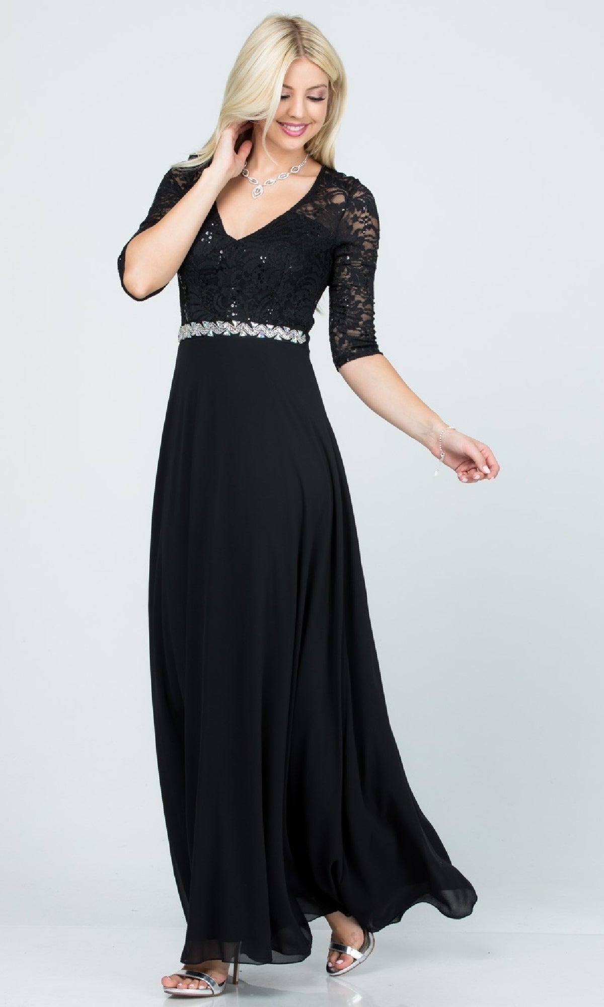 A woman models the Plus-Size A-Line Long Formal Dress with lace sleeves, a decorative waistband, and a flowing black skirt, paired with silver heels against a plain light background.