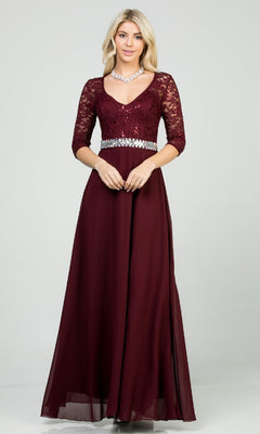 A blonde woman wears the Sleeved V-Neck Long A-Line Formal Dress 25434, featuring a sequin-lace bodice, three-quarter sleeves, rhinestone waistline, and chiffon floor-length skirt. She also accessorizes with a necklace.