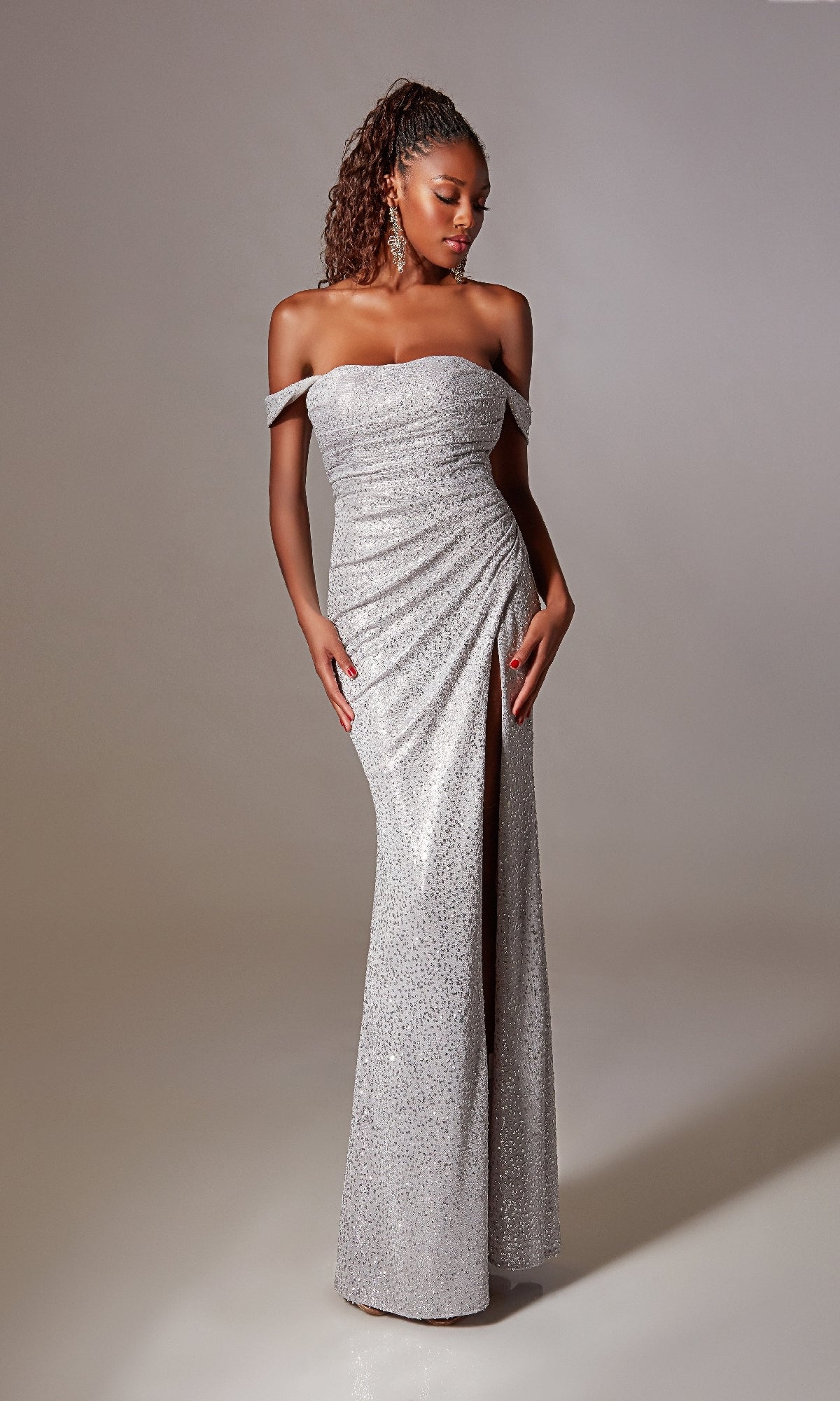 A woman in the Lace-Up Long Sequin Prom Dress: Aerie Couture 254, featuring sparkly sequins, off-the-shoulder style, and a thigh-high slit, stands against a plain light background.