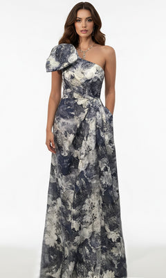 A woman stands against a white background wearing the Jovani 25663 long formal dress, which features an A-line skirt, one-shoulder design with a bold shoulder detail, and a grey and white floral pattern.