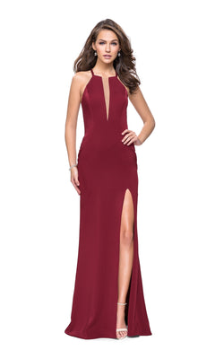A woman stands against a white background wearing the La Femme 25669 Long Prom Dress, a sleeveless burgundy gown with a plunging neckline and high thigh slit.
