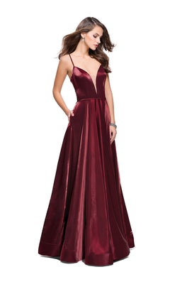 A woman wears the La Femme 25670 Long Prom Dress—a sleeveless, floor-length deep red satin A-line gown with thin straps, a deep V-neckline, and open back—standing against a white background.