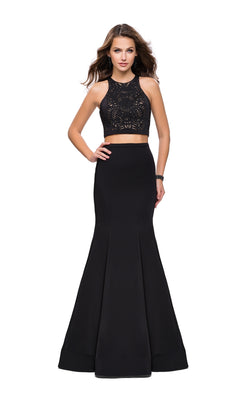A woman wearing the La Femme 25759 Long Prom Dress, a black two-piece with a lace crop top and fitted mermaid skirt, stands against a white background.