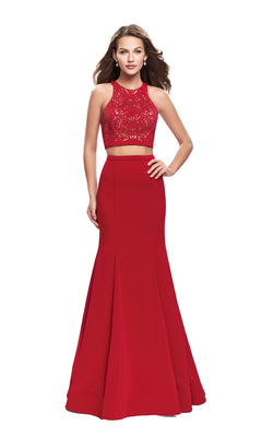 A woman wears the La Femme 25759 Long Prom Dress—a sleeveless, floor-length red two-piece with a lace crop top and flared skirt—while standing against a white background.