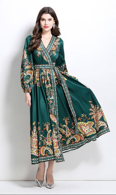 Woman in a forest green Long-Sleeve Paisley-Print Casual Maxi Wrap Dress stands against a white background, holding one side of the skirt.