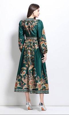 A woman faces away, wearing the Long-Sleeve Paisley-Print Casual Maxi Wrap Dress in deep green and silver low-heeled shoes.